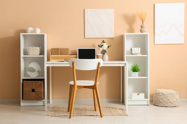 Stylish workspace with modern laptop and beautiful flowers in home office
