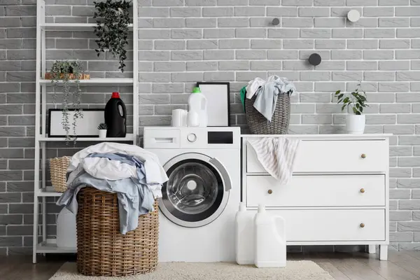 Çamaşır makinesi, çamaşır sepeti ve şifoniyeri olan şık bir banyo.