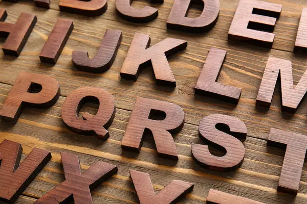 Ahşap arka planda birçok İngilizce harf, yakın plan