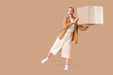 Bej arka planda bir paket kutusu olan genç bir kadın.