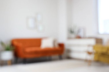 Oturma odasının bulanık manzarası, rahat kahverengi kanepe ve beyaz duvarın yanındaki çekmeceler.