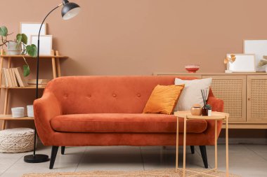 Rahat kanepesi ve kahverengi duvarı olan modern bir oturma odası.