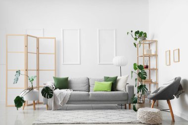 Oturma odasındaki kanepe, katlanan ekran ve canavar çiçekleri.