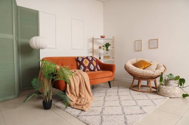 Rahat kahverengi kanepesi ve beyaz duvarın yanında çiçekleri olan modern bir oturma odası.