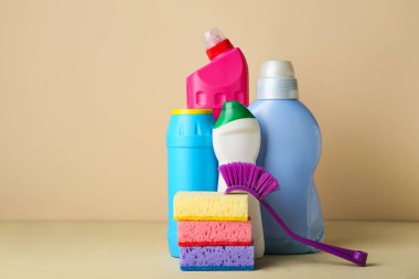 Bej arka planda temizlik malzemeleri ve şişe deterjan var.