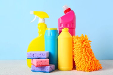 Mavi arka planda temizlik malzemeleri ve şişe deterjan, yakın plan.