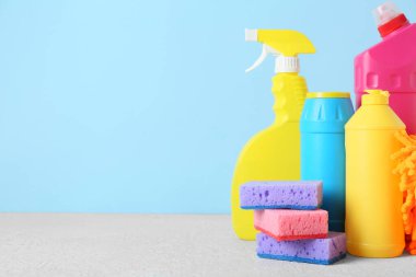 Mavi arka planda temizlik malzemeleri ve şişe deterjan, yakın plan.
