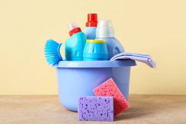 Temizlik malzemeleri ve bej arka planda bir şişe deterjan.