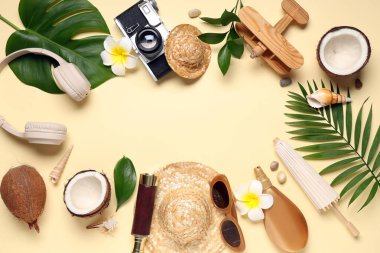 Plaj aksesuarları, hindistan cevizi, fotoğraf makinesi ve bej arka planda tropikal yapraklardan yapılmış çerçeve