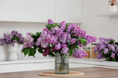 Mutfaktaki masada leylak çiçekli vazo.