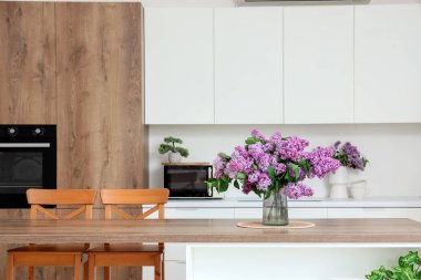 Mutfaktaki masada leylak çiçekli vazo.