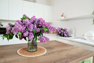 Mutfaktaki masada leylak çiçekli vazo.