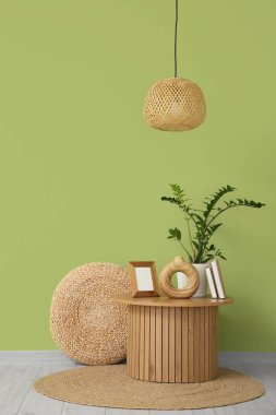 Oturma odasının iç tarafındaki yeşil duvarın yanında kitap, vazo ve çiçekli kahve masası.