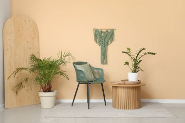 Kahve masası, sandalye ve bitkiler odanın içindeki bej duvarın yanında.
