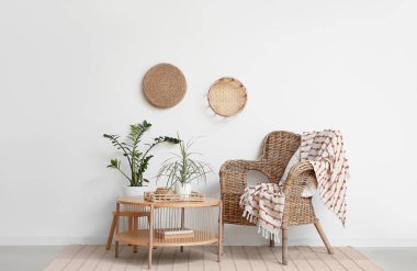 Kahve masası ve hasır sandalye odanın içindeki beyaz duvarın yanında.