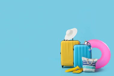 Mavi arka planda plaj aksesuarları olan bavullar.