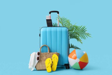 Mavi arka planda plaj aksesuarlarıyla dolu bavul.