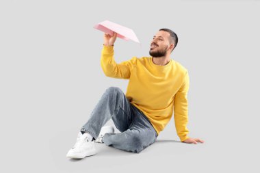 Kağıt uçakla arka planda oturan genç adam.