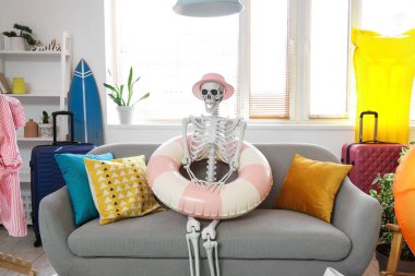 Oturma odasındaki kanepede plaj aksesuarlarıyla insan iskeleti.