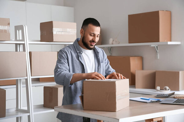 Продавец мужской упаковки посылки для клиента за столом на складе