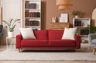 Kitaplıkları ve kırmızı kanepesi olan modern oturma odasının içinde.