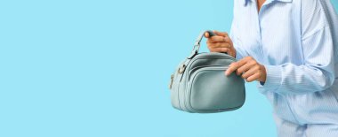 Mavi arka planda şık el çantalı genç Afro-Amerikalı kadın. Mesaj için yeri var.