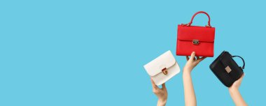 Mavi arka planda farklı tarz kadınların çantalarını tutan kadın elleri.