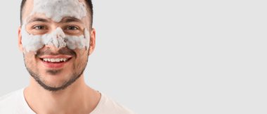 Yüzünde kozmetik balon maskesi olan yakışıklı, genç ve mutlu bir adam.