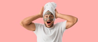 Yüzünde kozmetik kil maskesi olan yakışıklı, genç ve şaşkın bir adam.