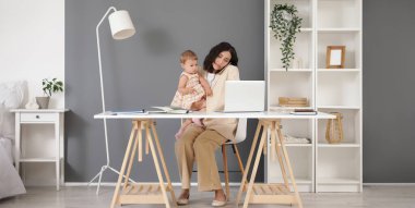 Çalışan anne evde bebeğiyle cep telefonuyla konuşuyor.