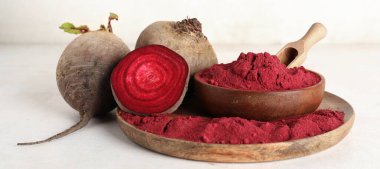 Canlı pancar tozu dolu ahşap bir tabak kepçe, kase ve beyaz arka planda taze pancar.