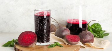 Beyaz arka planda fesleğenli bir bardak taze pancar suyu.