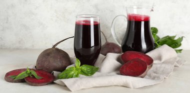 Beyaz arka planda fesleğenli bir bardak taze pancar suyu.