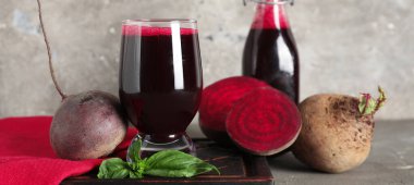 Gri arka planda fesleğen ve bir şişe taze pancar suyu.