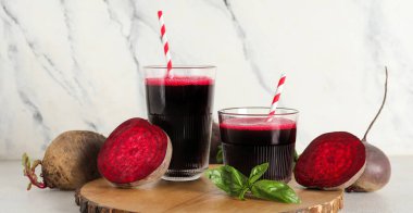 Beyaz arka planda fesleğenli ve sebzeli taze pancar suyu.