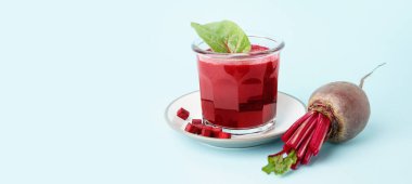 Bir bardak sağlıklı pancar suyu ve mavi arka planda ıspanak.