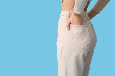 Mavi arka planda şık kotlu genç kadın.