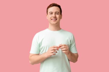 Pembe arka planda dudak merhemi olan yakışıklı bir genç.