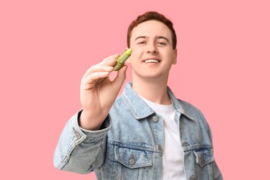 Pembe arka planda dudak merhemi olan yakışıklı bir genç.