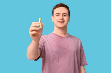 Mavi arka planda dudak merhemi olan yakışıklı bir genç.