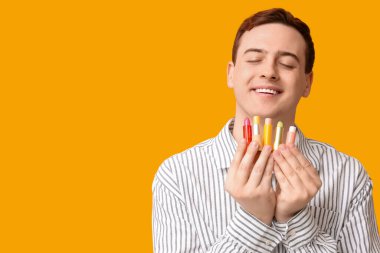 Sarı arka planda dudak merhemi olan yakışıklı bir genç.