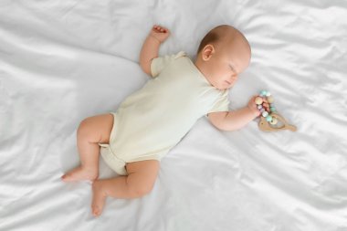 Çıngıraklı tatlı küçük bebek yatakta uyuyor, üst tarafta.