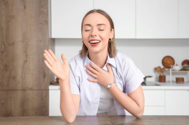 Mutfaktaki masada video sohbeti yapan genç bir kadın.