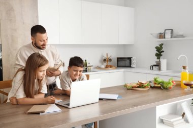 Babalarıyla evde ödev yapan sevimli çocuklar.