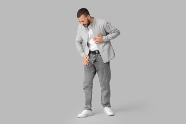 Gri arka planda kalp krizi geçiren genç bir adam.