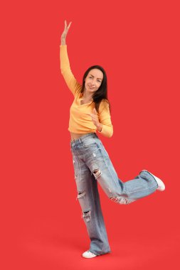 Kırmızı arka planda dans eden mutlu orta yaşlı kadın