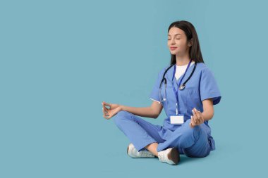 Genç bayan doktor mavi arka plan üzerinde meditasyon yapıyor.