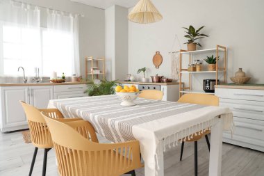 Mutfağın içinde tezgahlar, raf üniteleri ve yemek masası var.