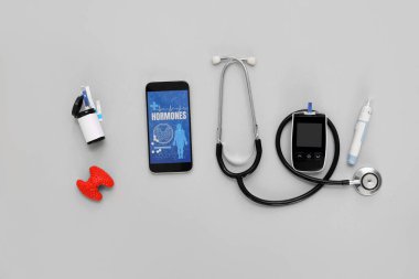 Glukometresi, lamba kalemi, steteskop ve gri arka planda tiroid bezi olan cep telefonu. Endokrinoloji kavramı