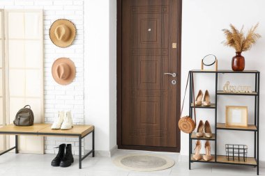 Beyaz duvarın yanında bank, katlanır ekran ve raf ünitesi olan modern koridorun içi